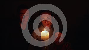 Woman with two children waiting at home by the candles during the blackout. Mother with her sons under candle lights