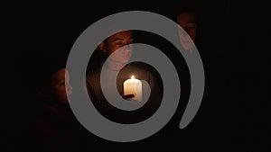 Woman with two children waiting at home by the candles during the blackout. Mother with her sons under candle lights