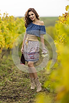 Woman with two glasses and a bottle of red wine in the vineyard on an autumn day