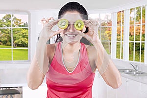 Woman with two slices of fresh kiwi