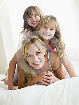 Woman and two young girls in bed playing