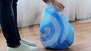 Woman tying bag with garbage at home