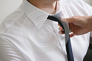 Woman tying a black tie around the neck of a man