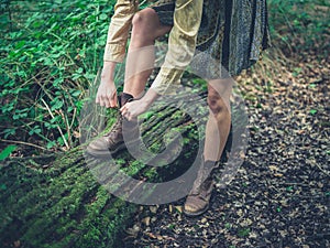 Woman tying her shoes in the forest