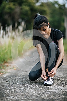 A woman tying her shoes to exercise in a fresh atmosphere.