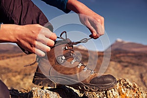 Woman tying hiking boot outdoors on trail in fall