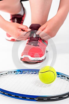 Woman tying lace near racket for tennis on a white