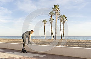 Woman tying the laces of roller skates before training outdoors.Active sport fitness lifestyle concept, on beach with palm trees