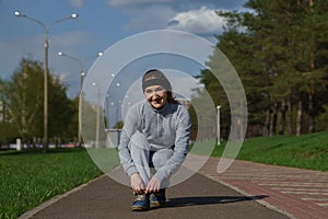 Woman tying shoe laces. Female sport fitness runner getting ready for jogging outdoors on forest path in spring or summer.