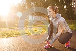 Woman tying shoe laces. Runner in the summer park