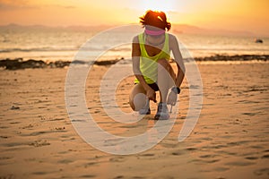 woman tying shoelace before running at sunset sandy beach