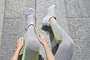 Woman tying shoelaces before running, sunny day