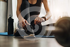 Woman tying shoes.A person running in tracksuit tying her shoelaces in gym