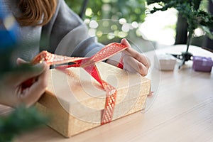 Woman tying xmas gift box with ribbon. Process of package xmas