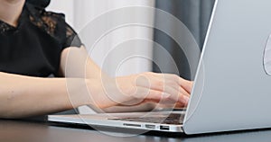 Woman types on laptop keyboard. Business lady in black dress working in office. Close up of female hands typing on computer