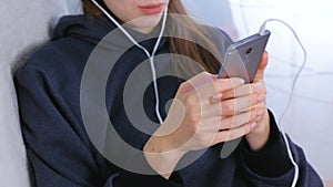 Woman types a message on a mobile phone, hands close-up.