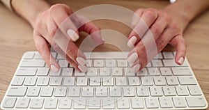Woman types on stylish wireless keyboard at wooden table