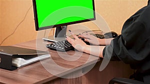 Woman typing on computer keyboard. Green monitor screen.