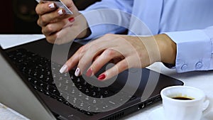 Woman typing credit card data on laptop computer. Close up of female hand holding card for online payment on computer.