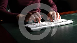 Woman typing on her computer keyboard at her work desk.