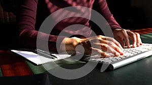 Woman typing on her computer keyboard at her work desk.