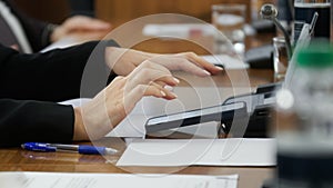 Woman typing on her mobile phone, a smartphone, while sitting at a desk with colleagues. Business in a call centre or stock photo