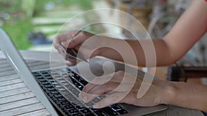 Woman typing on keyboard of computer laptop and using her credit card. Shopping online concept.