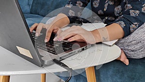 woman typing on a keyboard while working on laptop. Indian software developer is working from home