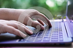Woman is typing on laptop keyboard, selective focus, working in evening at laptop of his house, hands closeup, concept of remote