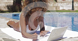 Woman typing laptop on poolside