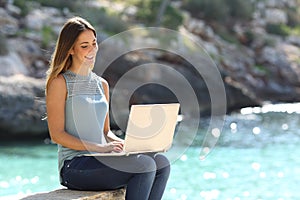 Woman typing on a laptop in a tropical beach