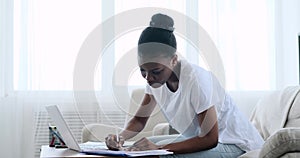 Woman typing on laptop and writing notes