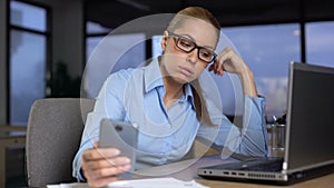 Woman typing message on mobile phone instead of working, bored at unloved job