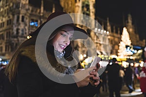 Woman typing on the phone at Christmas market in Munich