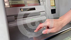 woman typing pin on keypad atm to withdraw money, bank cash machine