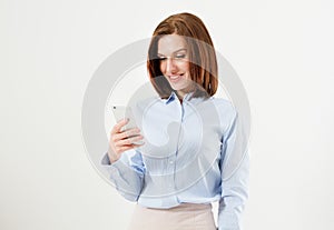 Woman typing text message on smart phone. Image of young woman standing on white background using mobile phone