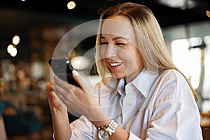 Woman typing text message on smart phone while sitting in a cafe