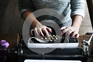 Woman typing vintage typewriter on wooden table