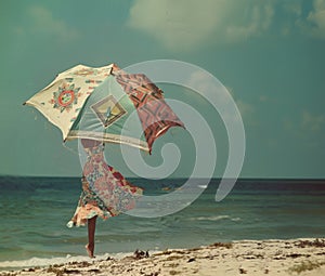 woman with umbrella on the beach, vintage color tone, retro style