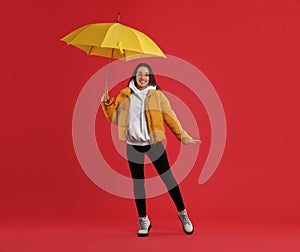 Woman with umbrella caught in gust of wind on red background