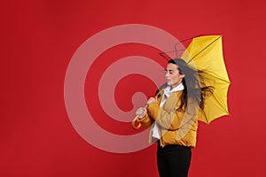 Woman with umbrella caught in gust of wind on red background. Space for text