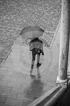 Woman with umbrella on cobbles place