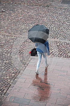 Woman with umbrella on cobbles place in the city