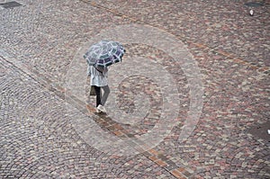 Woman with umbrella on cobbles place in the city