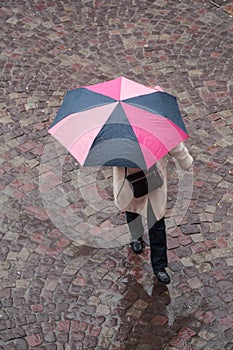 Woman with umbrella on cobbles place in the city