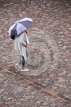 Woman with umbrella on cobbles place in the city