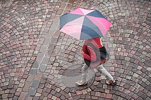 Woman with umbrella on cobbles place in the city