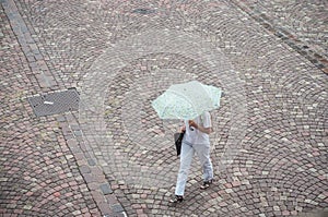 Woman with umbrella on cobbles place in the city