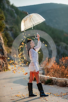 woman umbrella leaves , She holds him over her head, autumn leaves are falling out of him. Beautiful woman in a dress