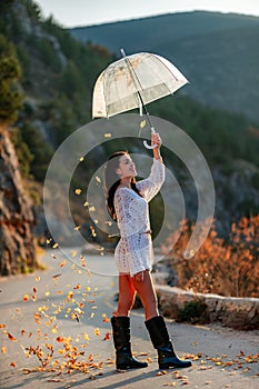 woman umbrella leaves , She holds him over her head, autumn leaves are falling out of him. Beautiful woman in a dress